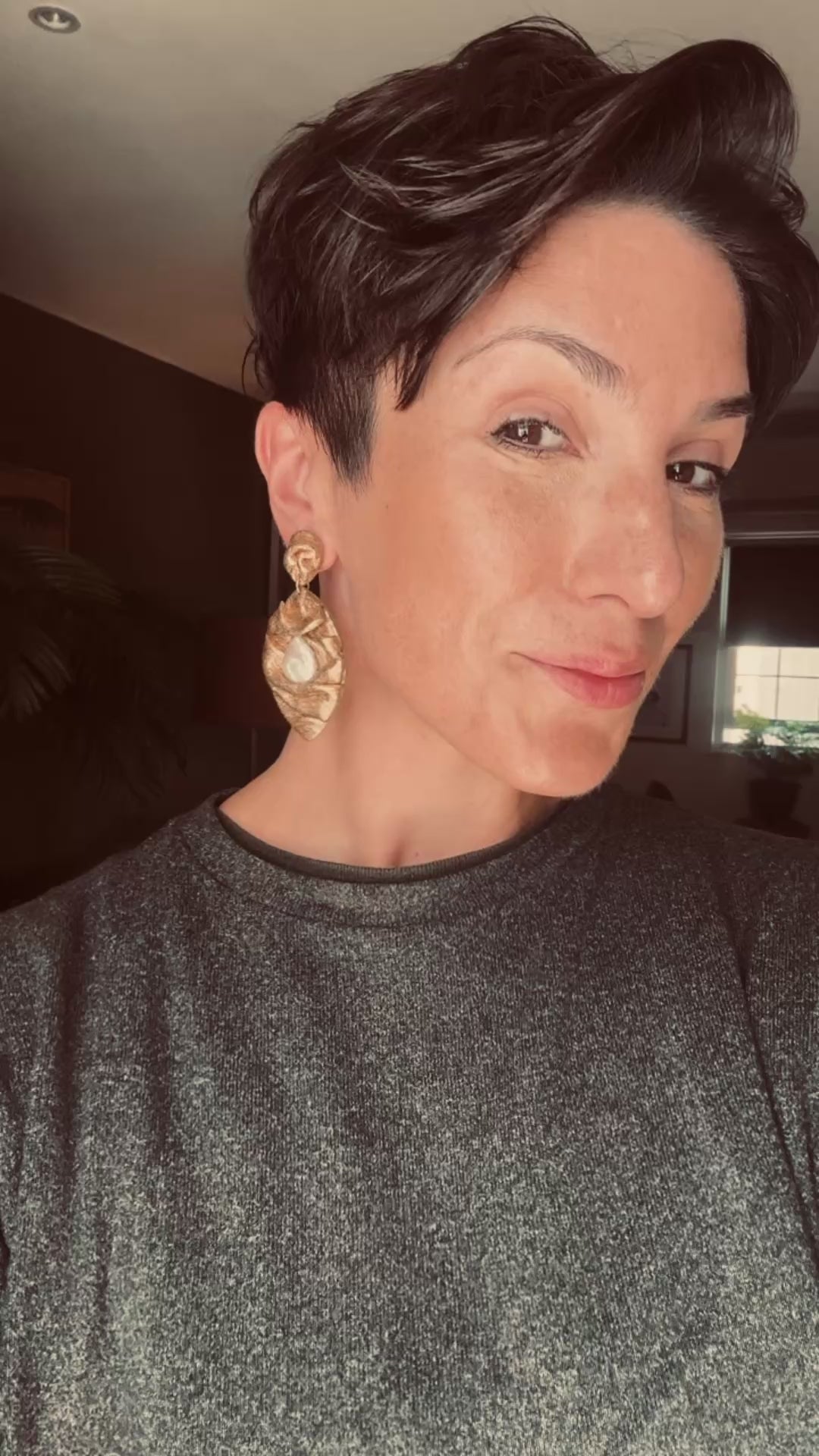 Model wears Ava & Azar handcrafted sculptural feather draped earrings with freshwater pearls 